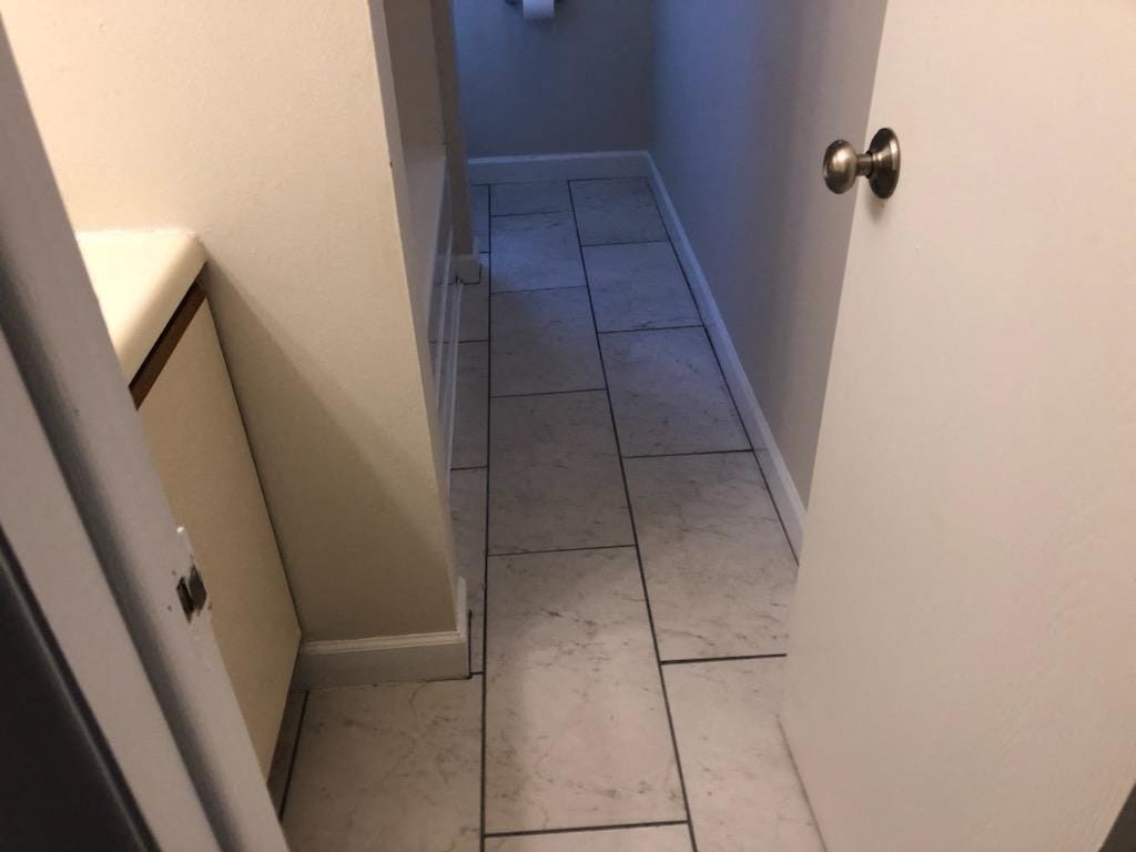 a bathroom with white tile floors and a white door