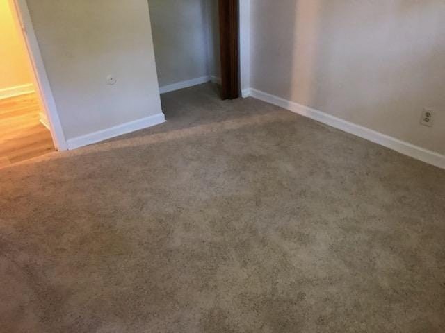 a carpeted room with a white wall and a door