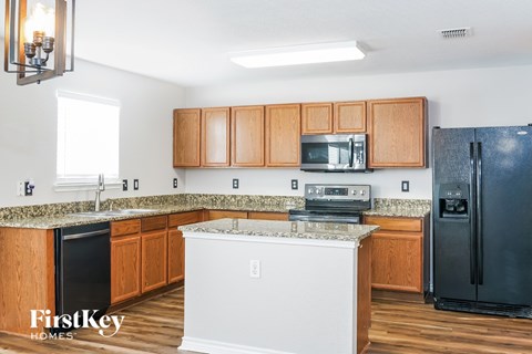 A kitchen with wooden cabinets and a black refrigerator.
