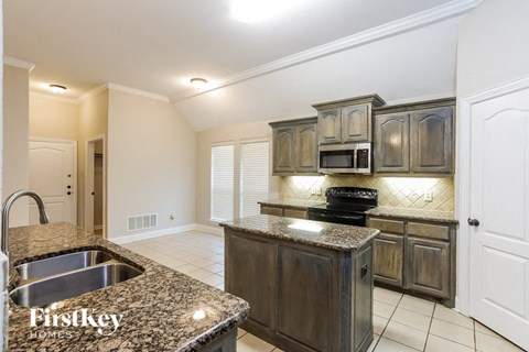 A kitchen with granite countertops and wooden cabinets.