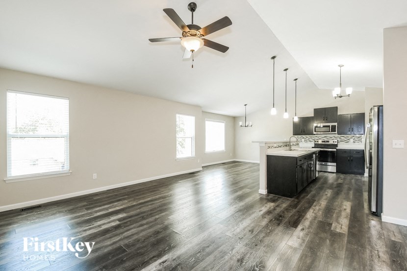 an open kitchen and living room with wood flooring and a ceiling fan