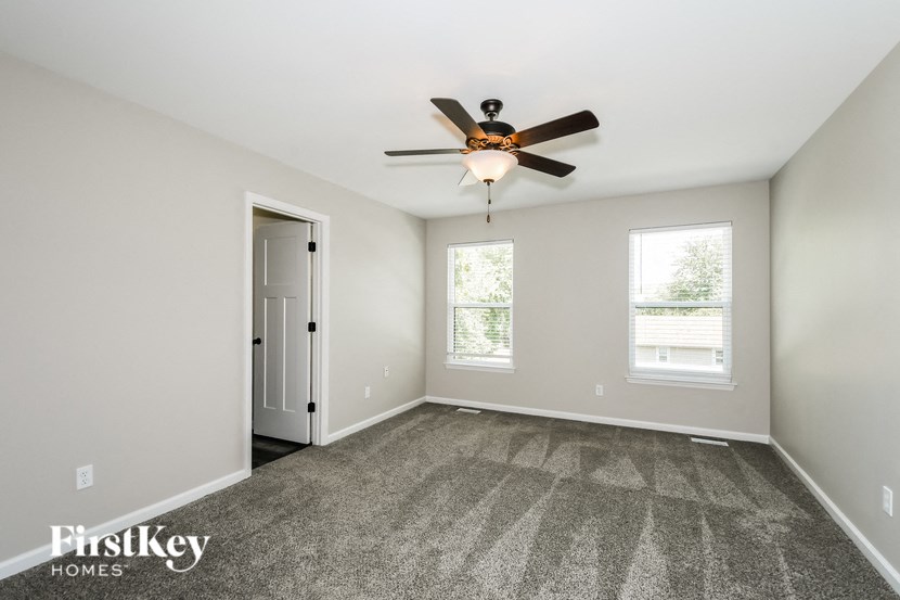 the spacious living room with ceiling fan and carpeting