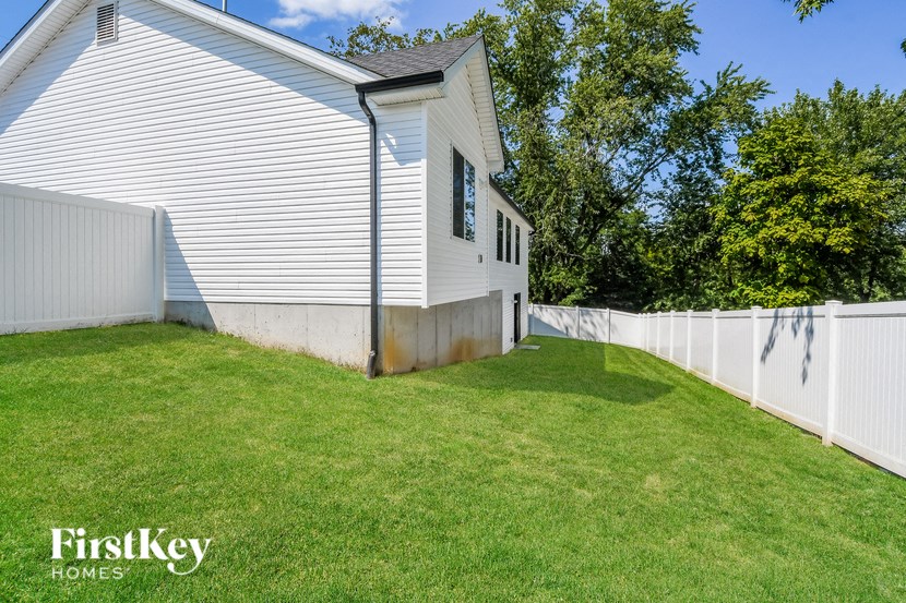 a backyard with a white house and a white fence
