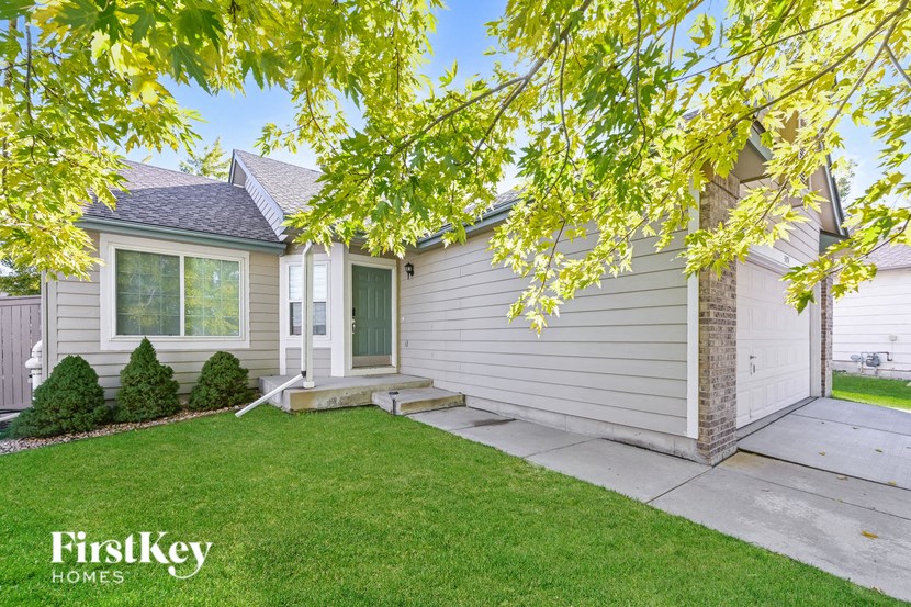 A house with a green lawn and a tree branch in the foreground.