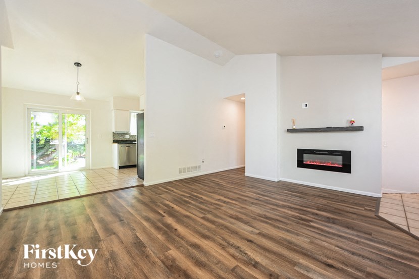 A spacious living room with a fireplace and wooden floors.