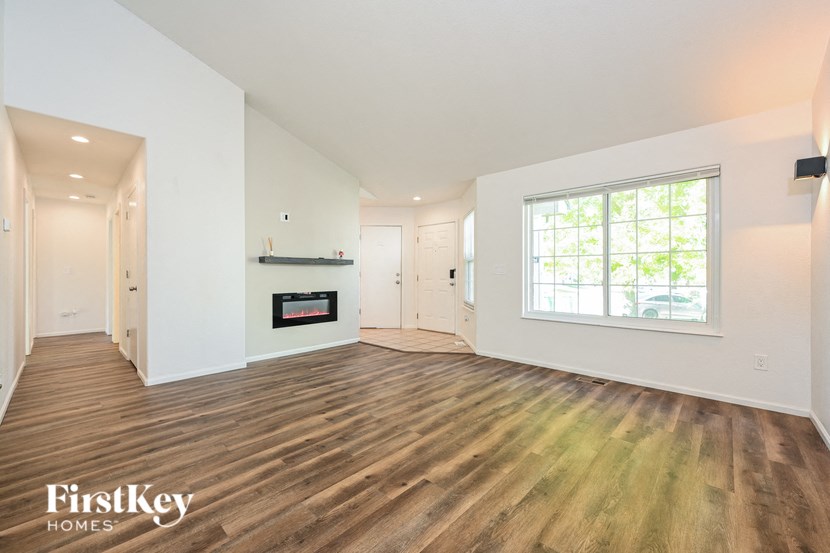 A spacious living room with wood flooring and a fireplace.
