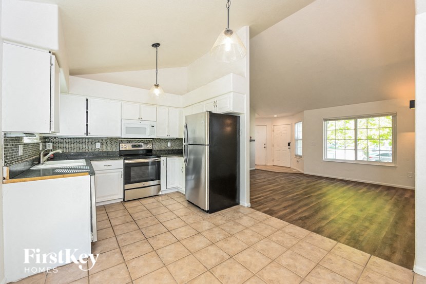 A kitchen with white appliances and a black refrigerator.