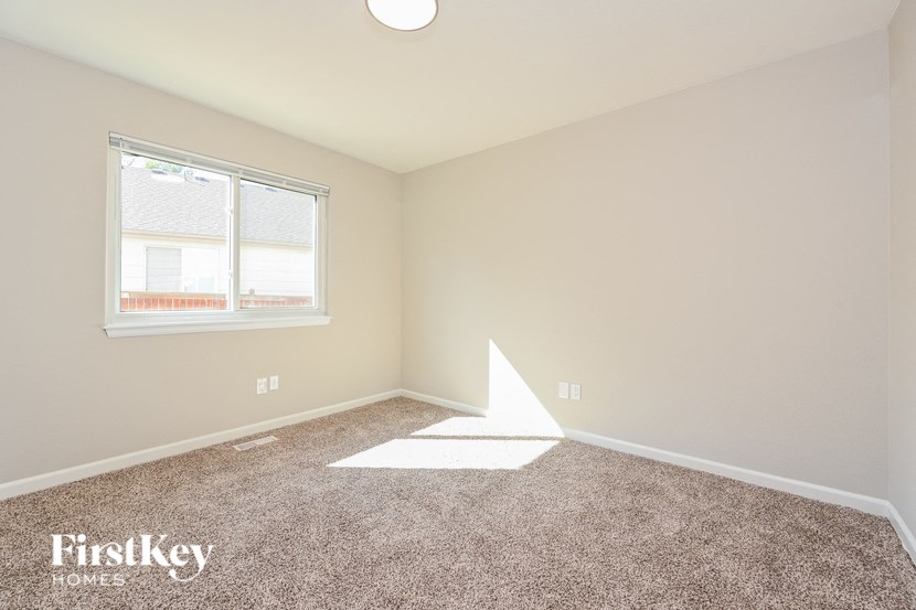 A room with a carpet floor and a window letting in light.