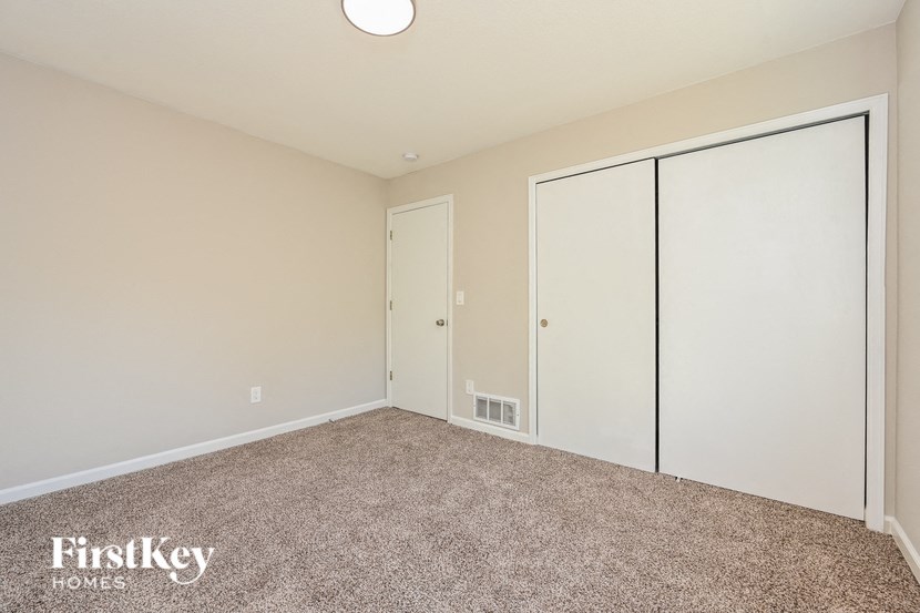 A bedroom with a carpeted floor and a white ceiling light.