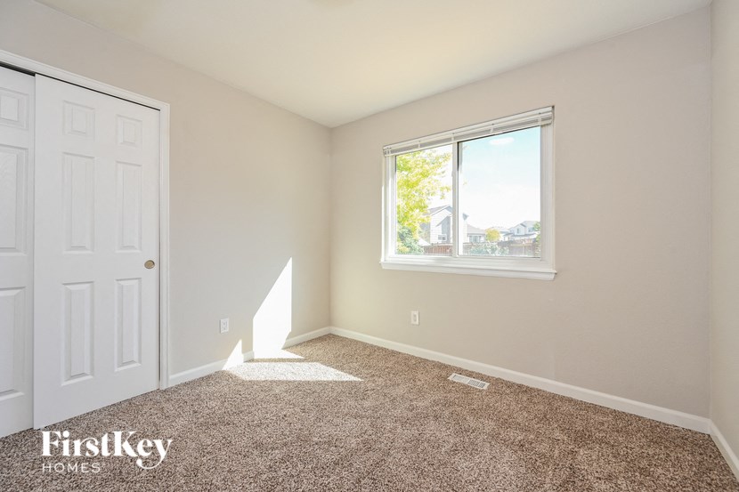 A room with a carpeted floor, a window, and a door.