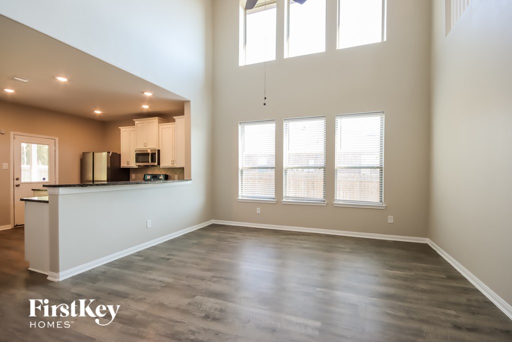 A spacious kitchen and living room with wood flooring and large windows.