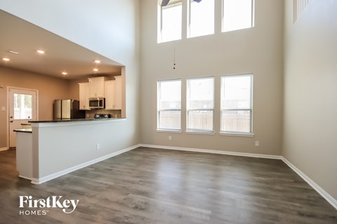 A spacious kitchen and living room with wood flooring and large windows.