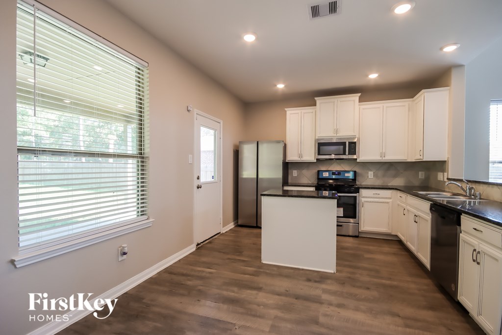A kitchen with a refrigerator, microwave, and oven.