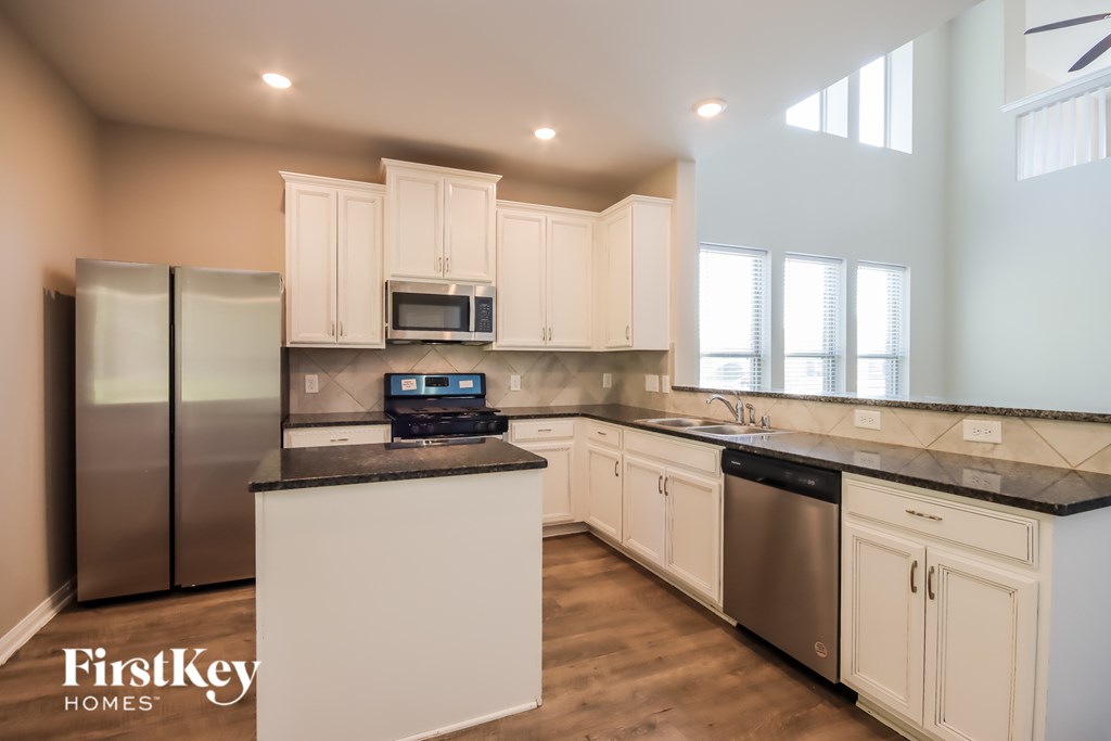 A kitchen with a refrigerator, microwave, and sink.