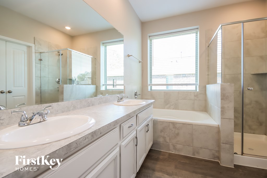 A bathroom with a large mirror, a bathtub, and a walk-in shower.