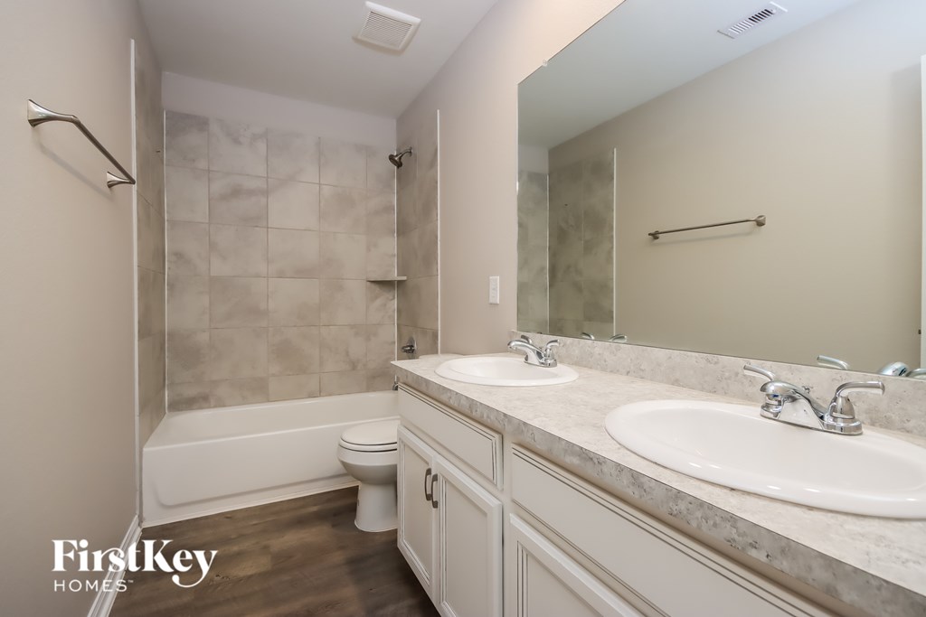 A bathroom with a marble tile shower and a white toilet.