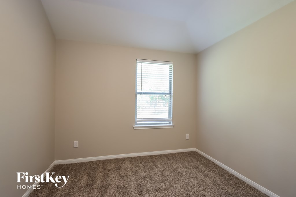 A room with a carpeted floor and a window with blinds.