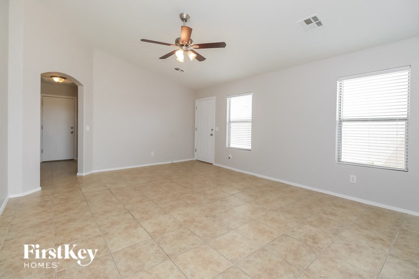 an empty living room with a ceiling fan and a tiled floor
