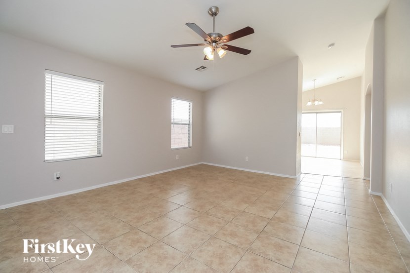 an empty living room with a ceiling fan and a tiled floor