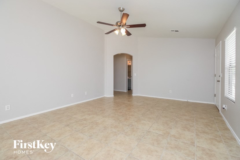 an empty living room with a ceiling fan and a tiled floor