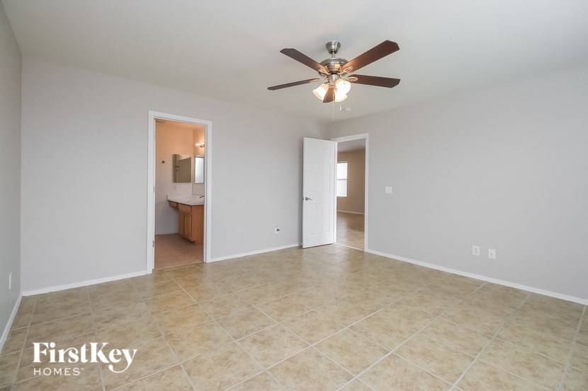 an empty living room with a ceiling fan and a tile floor