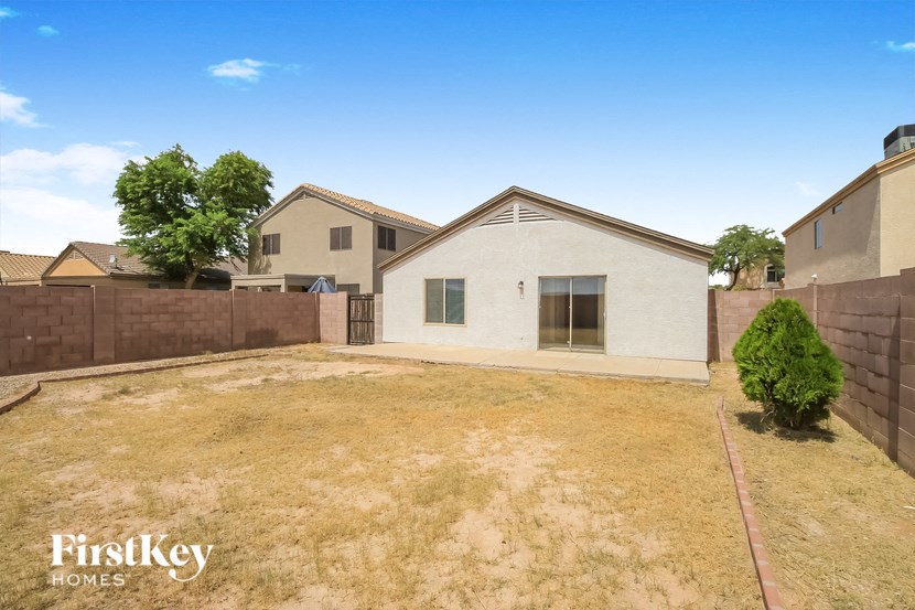 a backyard with a white house and a fence