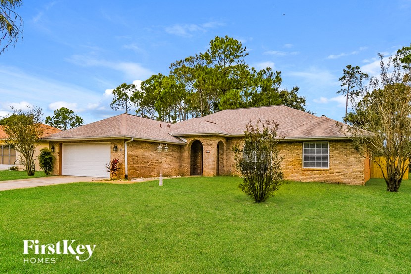 the front of a brick house with a lawn and a garage