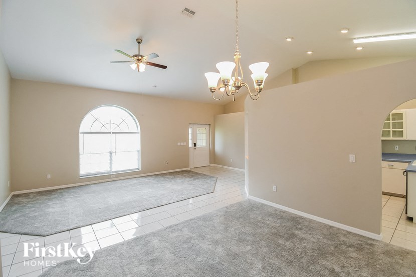 an empty dining room with a chandelier and a window