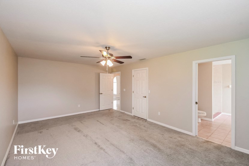 an empty living room with a ceiling fan and a bathroom