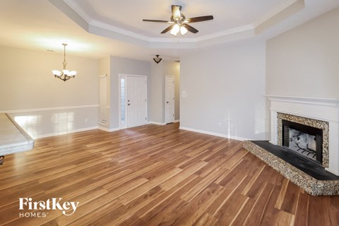 A spacious room with wooden floors and a fireplace.