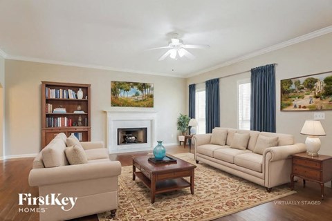 A living room with a fireplace, two couches, a coffee table, and a bookshelf.