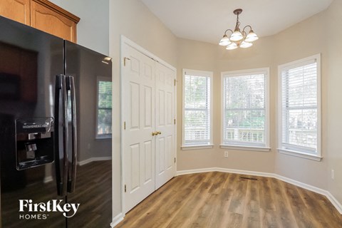 A kitchen with a refrigerator and wooden floors.