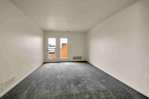 A room with a carpeted floor and a door leading to another room.