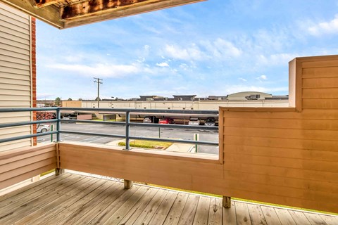 A wooden deck with a view of a parking lot and buildings.