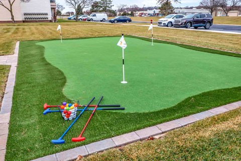 A miniature golf course with a green surface and a basket of balls.