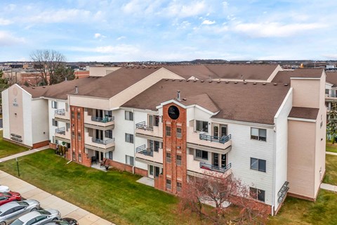 Apartment building with a brown roof and a parking lot in front.