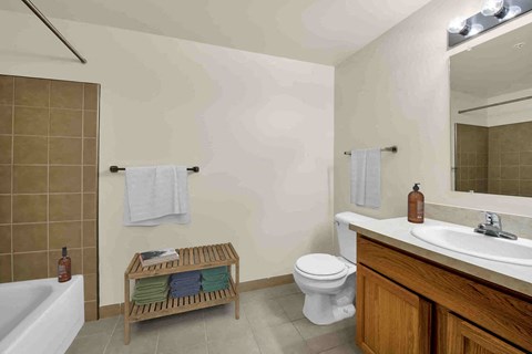 A bathroom with a white toilet, a wooden bench, and a white bathtub.