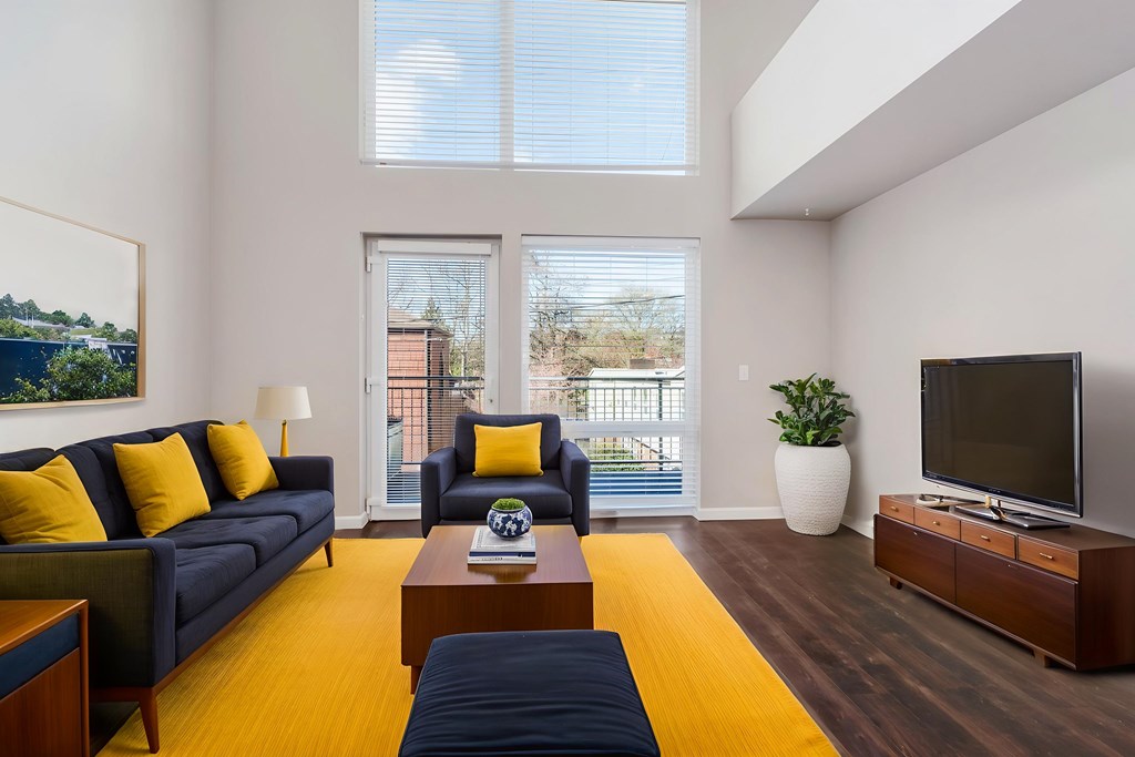 A living room with a blue couch and yellow pillows.