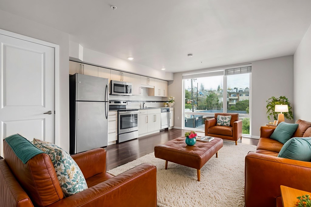 A modern living room with brown leather couches and a kitchen area in the background.