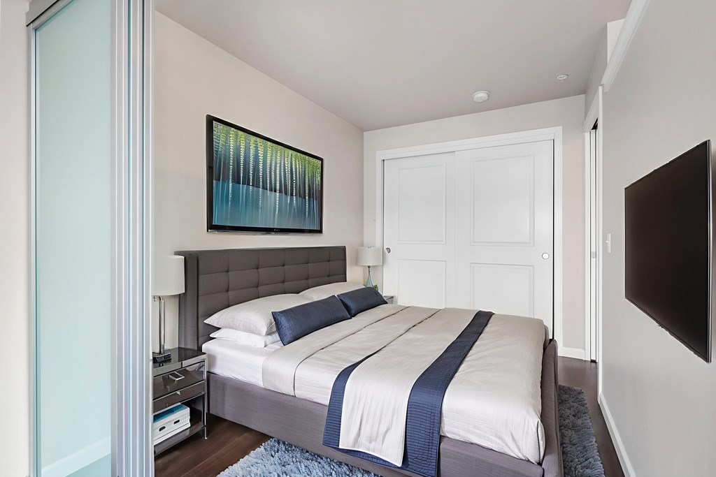 A bedroom with a bed, nightstand, and a painting on the wall.