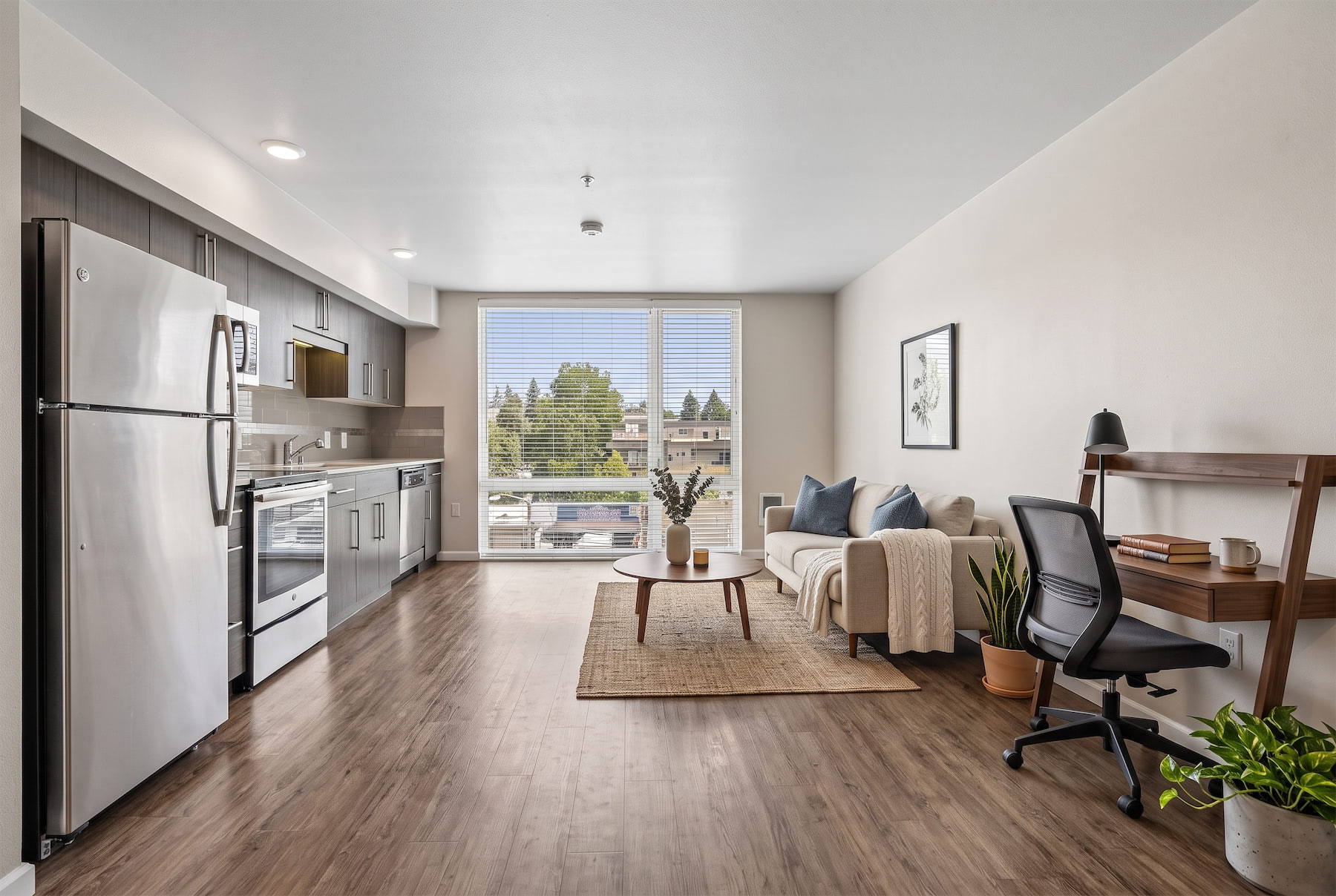 A modern kitchen with a refrigerator, a dining table with chairs, and a living area with a couch.
