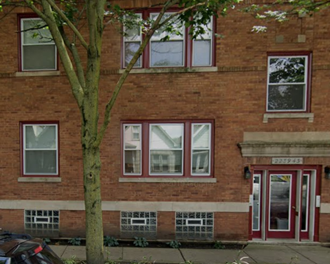 a brick building with red windows and a tree in front