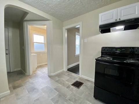 A kitchen with a black stove top oven and a tiled floor.