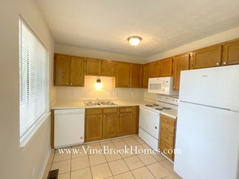 a full view of a kitchen with white appliances and wooden cabinets