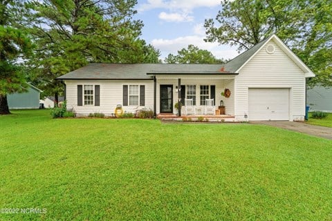 A white house with a green lawn in front.