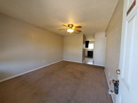 an empty living room with a ceiling fan