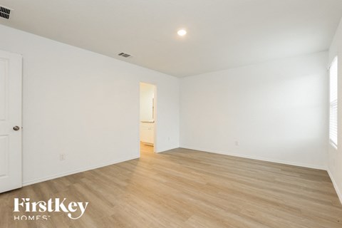 the living room and dining room of a house with white walls and wood floors