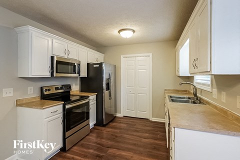 A kitchen with white cabinets and a wooden counter top.