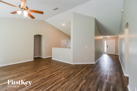 A spacious room with wooden floors and a ceiling fan.