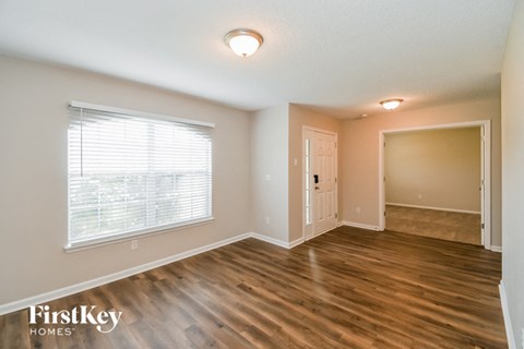 A room with wooden floors and a window with blinds.